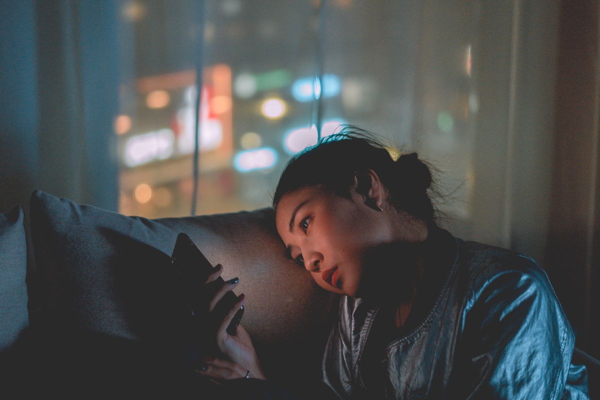 夜の街明かりの中でスマホを見つめる女性